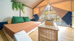 Quarto com cama, planta pendurada, mesa e vista para o exterior.