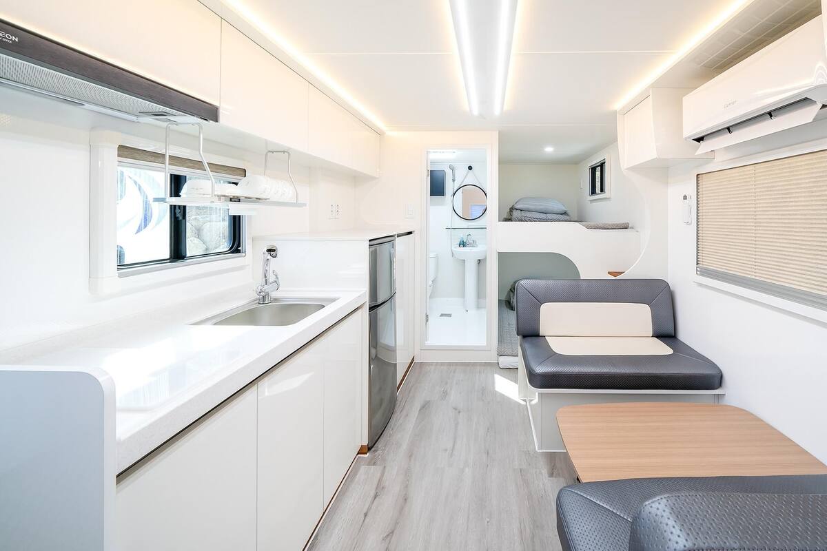 A compact kitchenette with a sink, stove, and storage cabinets.