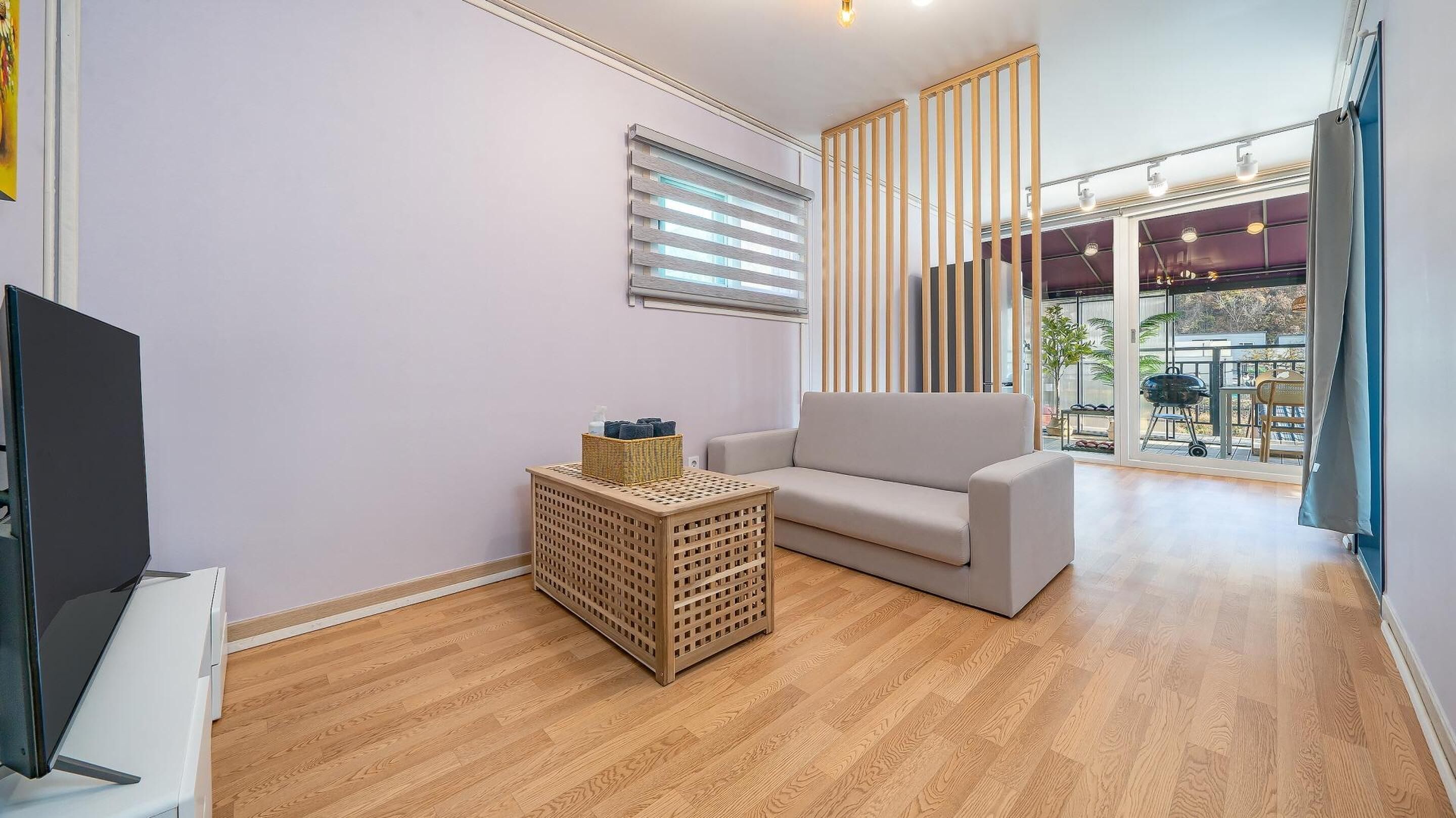 A modern living room with a sofa, a television, and a wooden floor.
