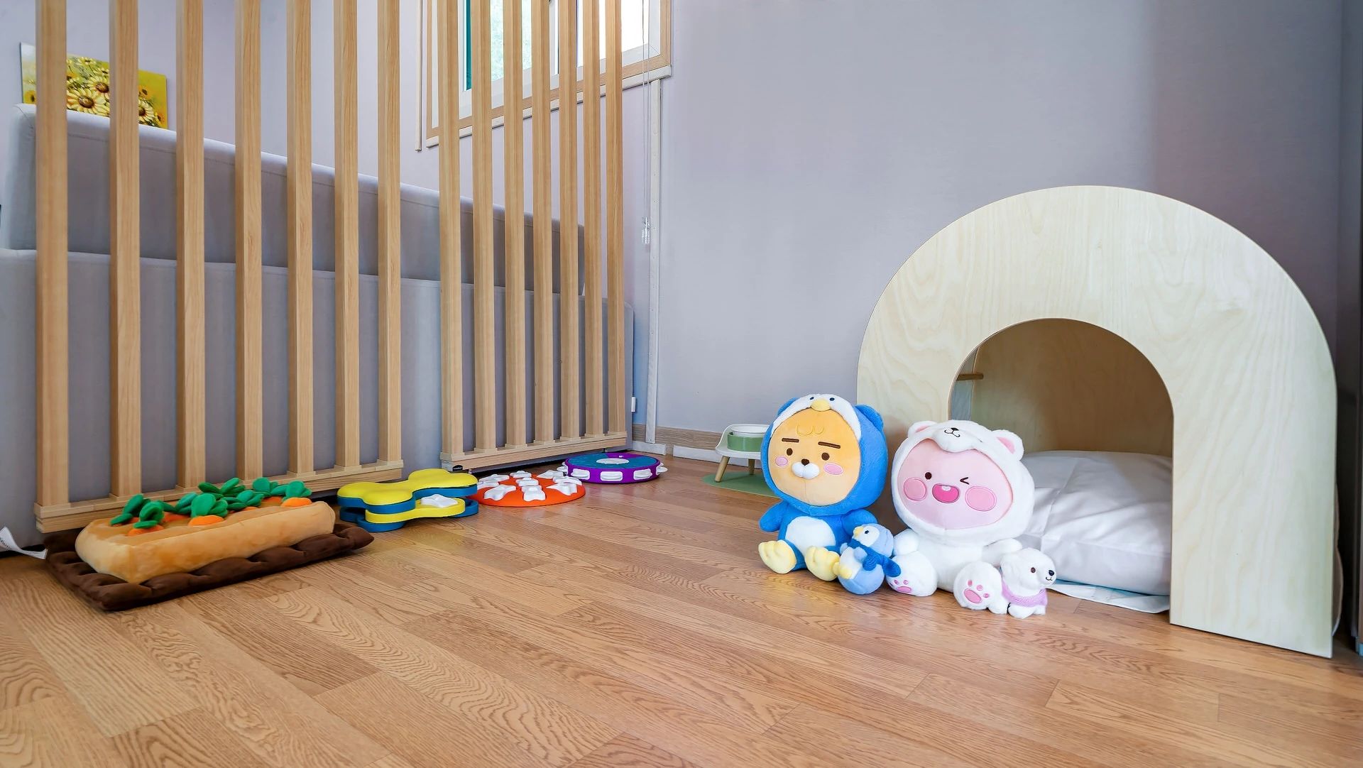 Zona de juegos para niños con una cuna de madera, un corralito y varios juguetes.