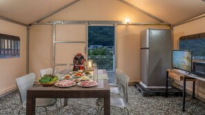 A tented outdoor dining area with a table set for a meal, a refrigerator, and a television. - Gapyeong Ddobagi Pet & Spa Glamping (Gapyeong)