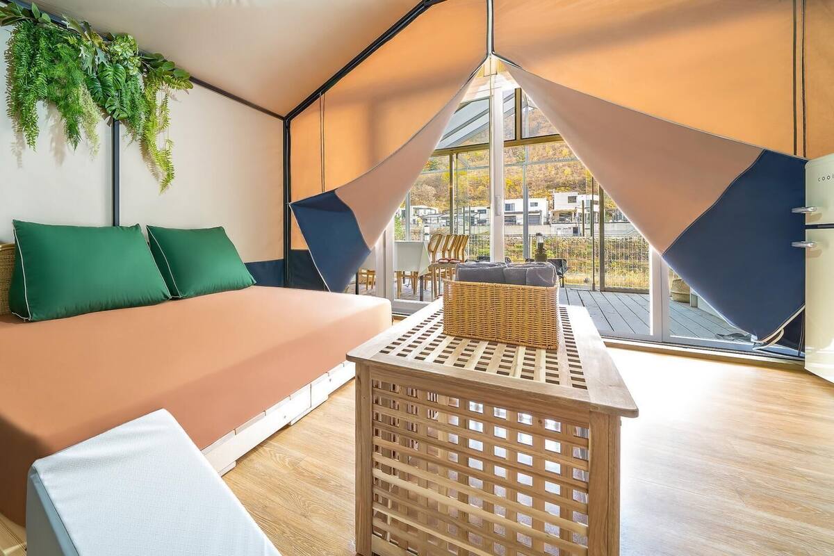 A modern room with a bed, a small table, and a view through large windows.