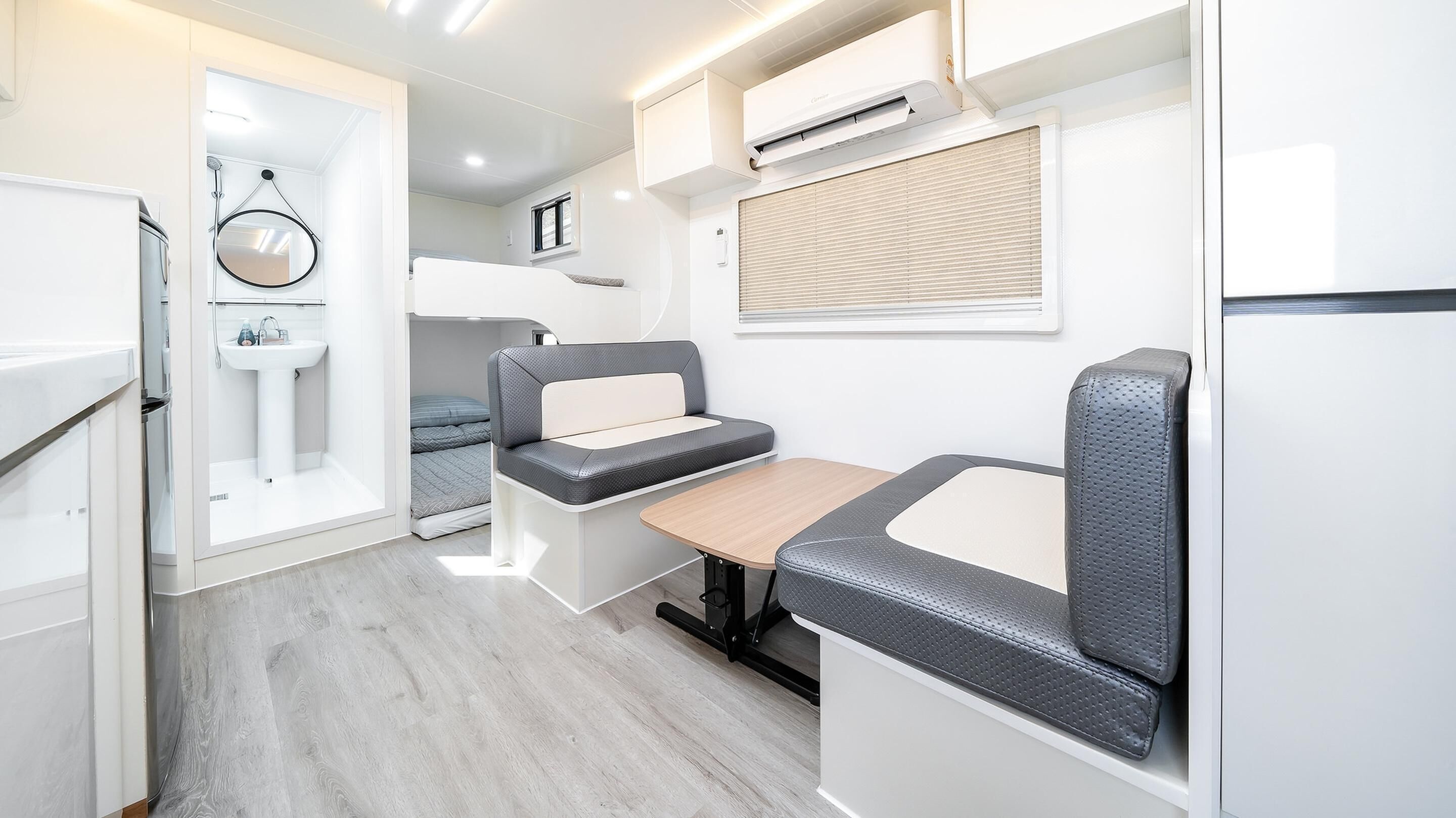 Una kitchenette compacta con un lavamanos, un ventanal pequeño y un equipo de aire acondicionado.