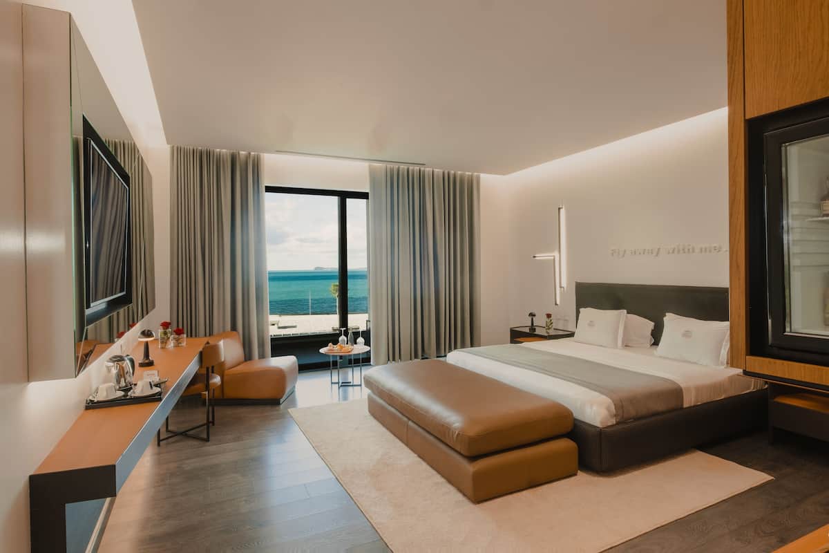 Ein modernes Hotelzimmer mit einem großen Bett, einem Schreibtisch und Blick aufs Meer.