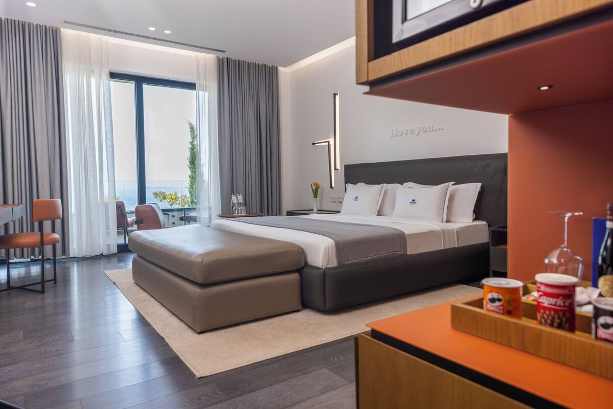 Ein modernes Hotelzimmer mit einem großen Bett, einem Schreibtisch und Blick ins Freie.