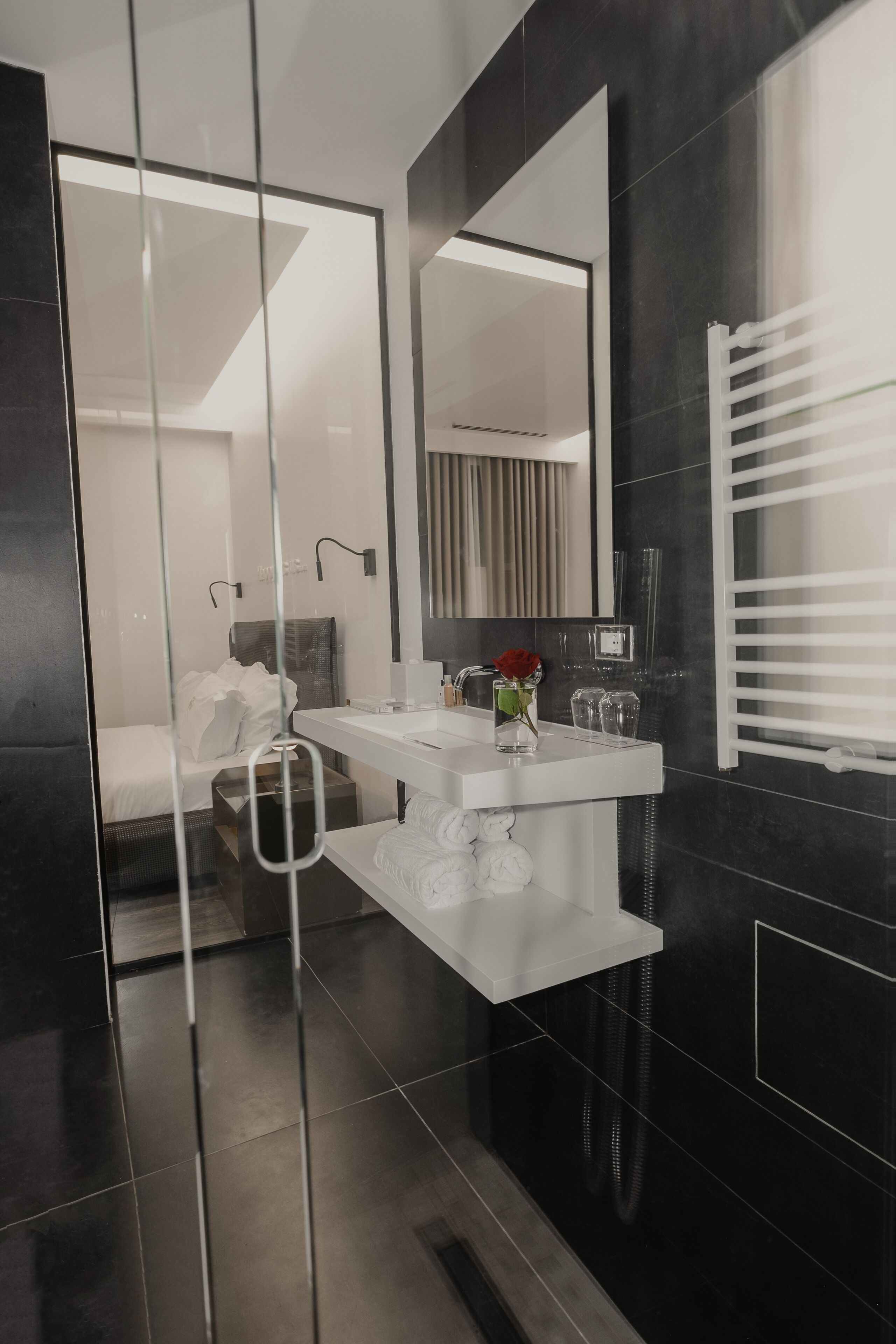 A modern bathroom with a glass partition, a white vanity, a large mirror, and a shower area.