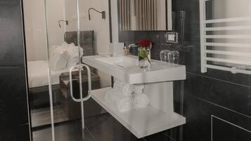 A modern bathroom with a glass partition, a white vanity, a large mirror, and a shower area.