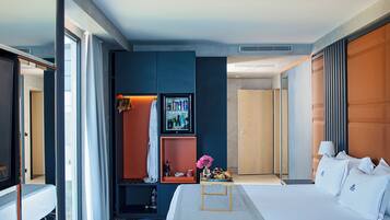 Een moderne hotelkamer met een groot bed, een kledingkast, een kaptafel met spiegel en een zichtbare badkamer door een open deur.