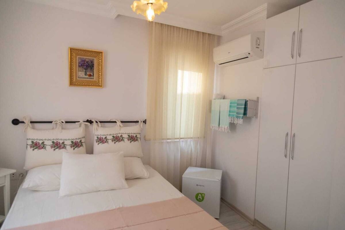 A bedroom with a bed, a nightstand, an air conditioning unit, and a wardrobe.