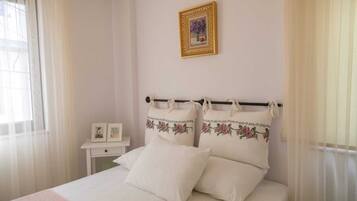 A neatly arranged bedroom with a bed, a bedside table, and a wall-mounted picture frame.