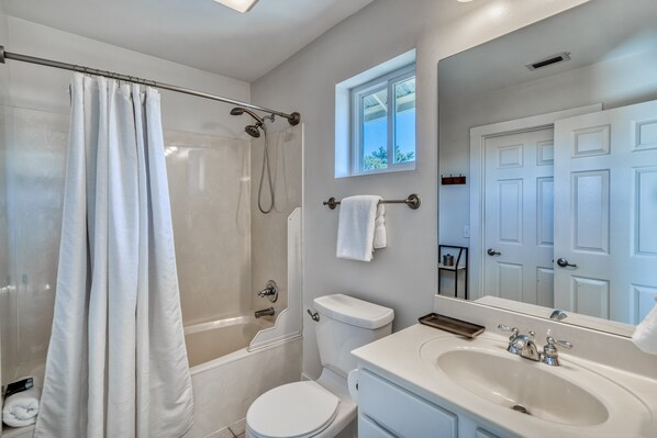 A bathroom with a shower, toilet, sink, and a window providing natural light. - Golf Cart | Pool | Gym | South of 30a (Santa Rosa Beach)