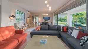 A modern living room with a sectional sofa, a coffee table, and a dining area with chairs.