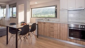 A modern kitchen with wooden cabinets, a stainless steel stove, and a large window offering a view of the outdoors.