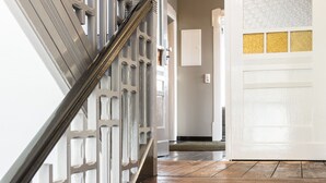 A wooden staircase with a metal railing leading to a door with a textured wall.