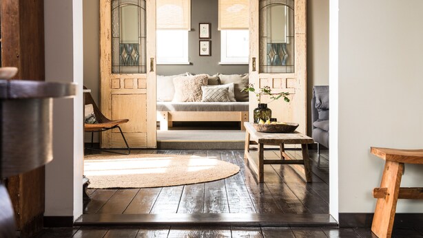 A cozy room with a wooden door, a sofa, a small table, and a rug.