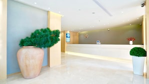 A hotel reception area with a large potted plant, a reception desk, and a digital information board. - Ji Hotel Shanghai Oriental Pearl Tower (Shanghai)