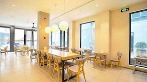 A spacious dining area with high ceilings, large windows, and modern furniture.