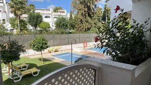 A pool area with a small pool, yellow lounge chairs, and a white building in the background. - Live in Paradise (Marbella)