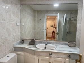 A modern bathroom with a large mirror, a sink, and a shower. - Live in Paradise (Marbella)
