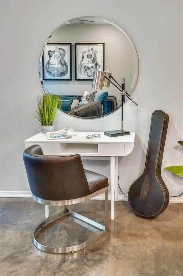 A modern office space with a white desk, a black leather chair, a round mirror, and a guitar against the wall. - New, Luxury Home, Private Roof Deck (Nashville)