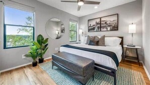 A bedroom with a bed, a ceiling fan, a window, a mirror, and a bedside table. - New, Luxury Home| Private Roof Deck (Nashville)