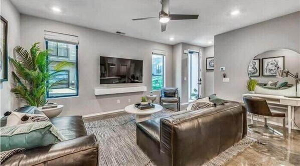 A modern living room with a fireplace, leather sofas, a TV, and a dining area.
