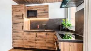 A modern kitchen with wooden cabinets, a built-in microwave, and a black countertop.