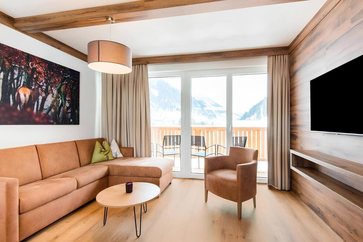 A modern living room with a sofa, armchair, coffee table, and a painting on the wall.