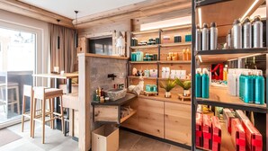 A modern kitchen with wooden cabinetry, a stone backsplash, and a built-in stove. There are shelves with various kitchen items and a dining area with a table and chairs.