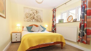 A bedroom with a bed, bedside tables, a radiator, and curtains. - La'l Skaithe (Kirkby Stephen)