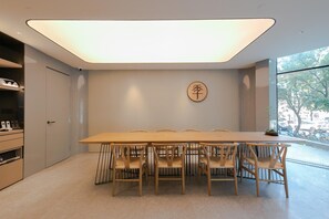 Une salle de conférence avec une longue table et des chaises, un luminaire au plafond et une horloge fixée au mur.