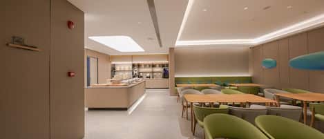 A modern dining area with a central counter, seating, and a view of the kitchen.