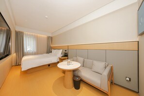 Une chambre d’hôtel avec un lit, un canapé, une petite table ronde et un téléviseur.