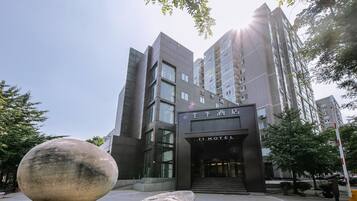 A modern hotel building with a prominent entrance and a large spherical sculpture in the foreground.