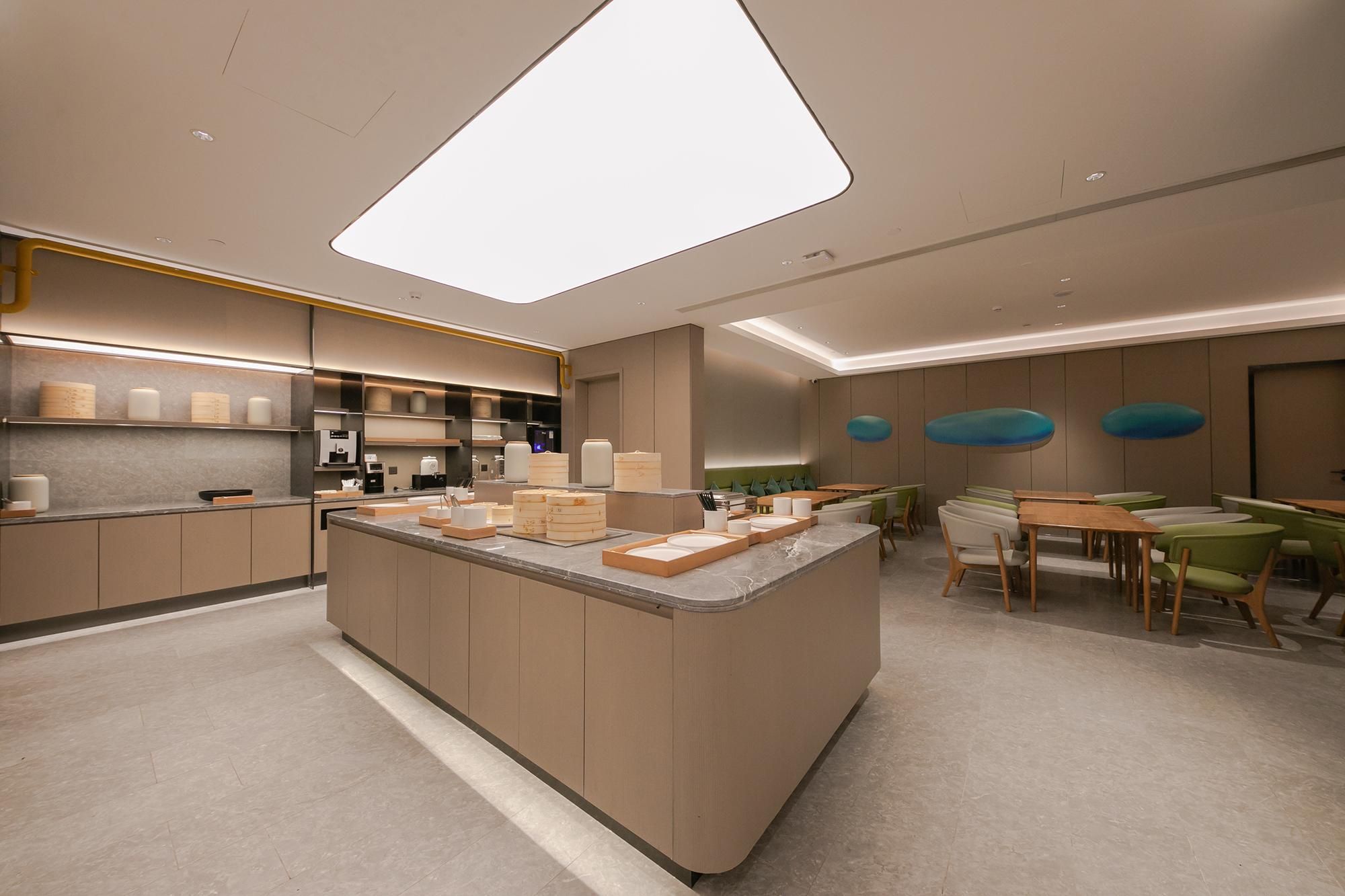 Una cocina moderna con una isla central, electrodomésticos integrados y un comedor con sillas verdes.