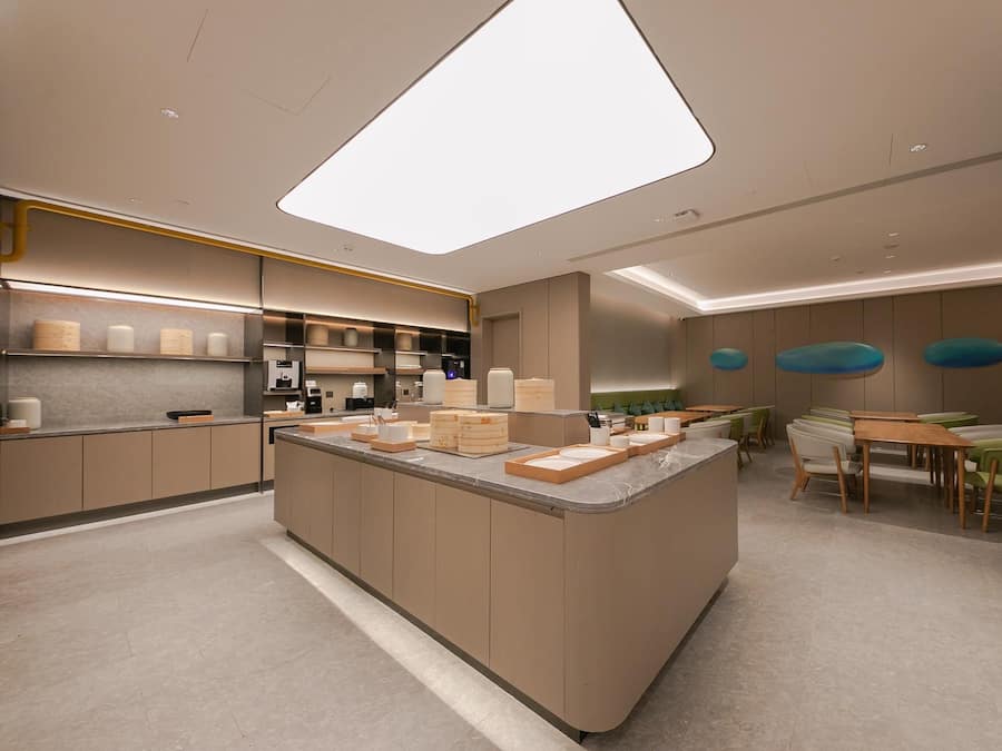 Uma cozinha moderna com ilha central, eletrodomésticos embutidos e área de refeições com cadeiras verdes.