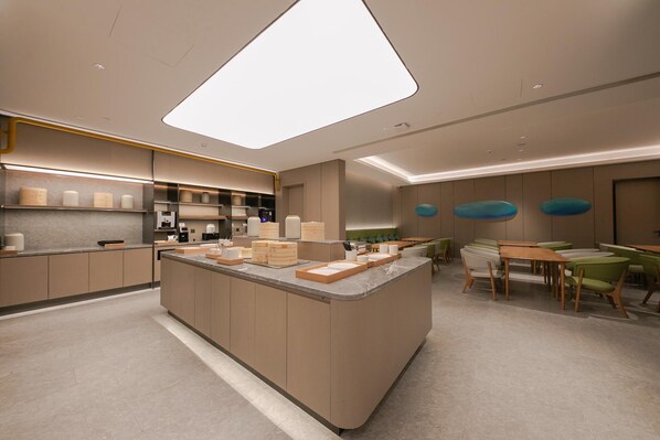 Une cuisine moderne dotée d’un îlot central, d’appareils électroménagers intégrés et d’un coin repas avec des chaises vertes.