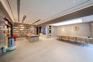 A modern interior with a long table and chairs, a vending machine, and a wall with a circular design.