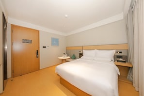 A hotel room with a bed, bedside table, and a door. - Ji Hotel (Beijing)