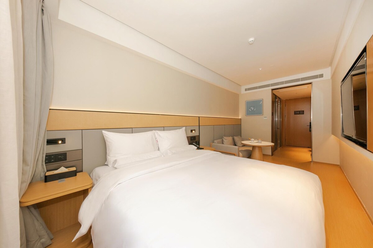Une chambre d’hôtel avec un grand lit, des tables de chevet, un bureau et une petite table ronde avec une chaise.