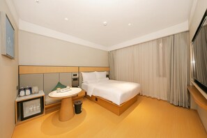 Une chambre d’hôtel avec un lit, une table de chevet et une petite table avec une lampe.