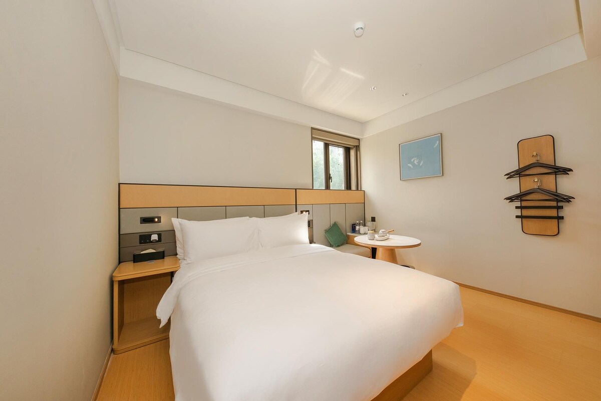 Une chambre d’hôtel avec un lit, une table de chevet et une petite table ronde sur laquelle se trouvent une tasse et une soucoupe.