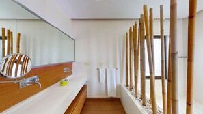 A modern bathroom with a wooden vanity, a large mirror, and bamboo decor.