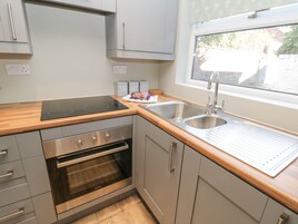 Una cocina moderna con armarios grises, un lavamanos de acero inoxidable, un horno empotrado y una ventana con vistas al exterior.