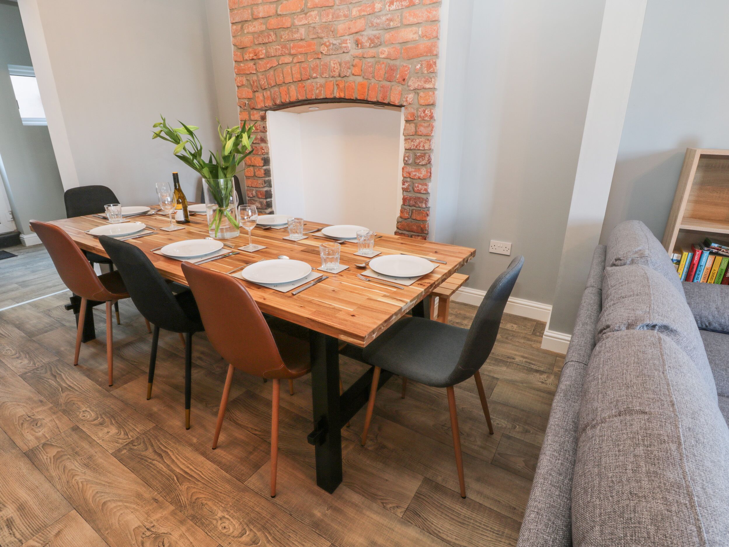 Un comedor con pared de ladrillo, mesa de madera y sillas.