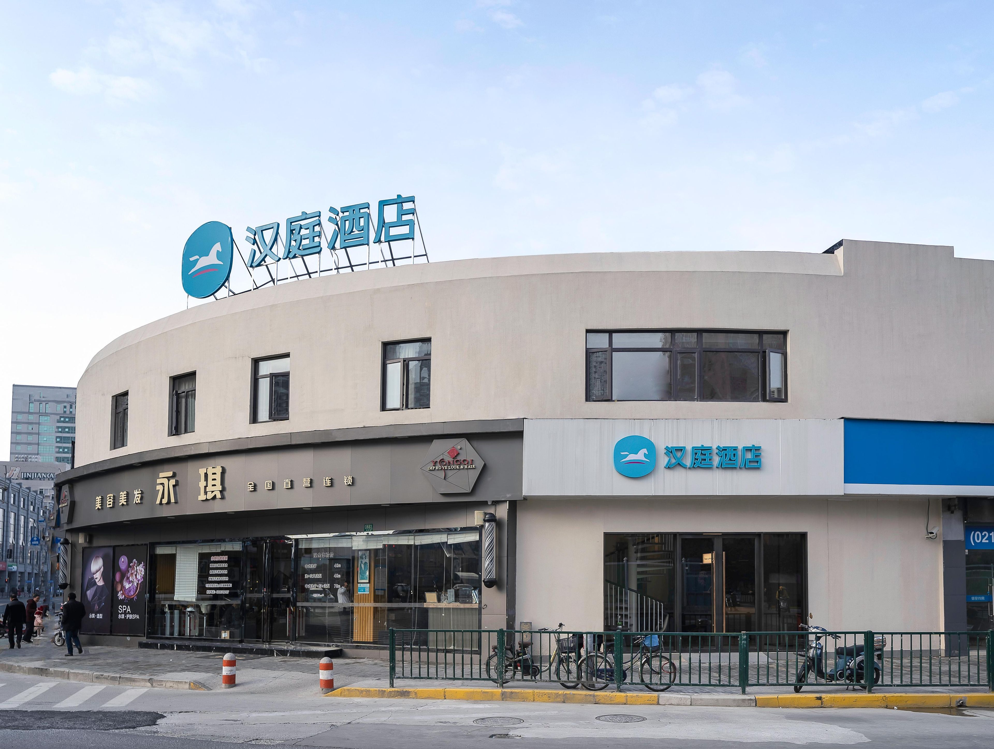A hotel with a curved facade, a signboard with Chinese characters, and a bicycle parked in front.