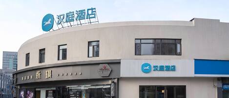A hotel with a curved facade, a signboard with Chinese characters, and a bicycle parked in front.