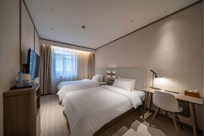 Une chambre d’hôtel avec deux lits, un bureau, une chaise, une télévision et une fenêtre avec des rideaux.
