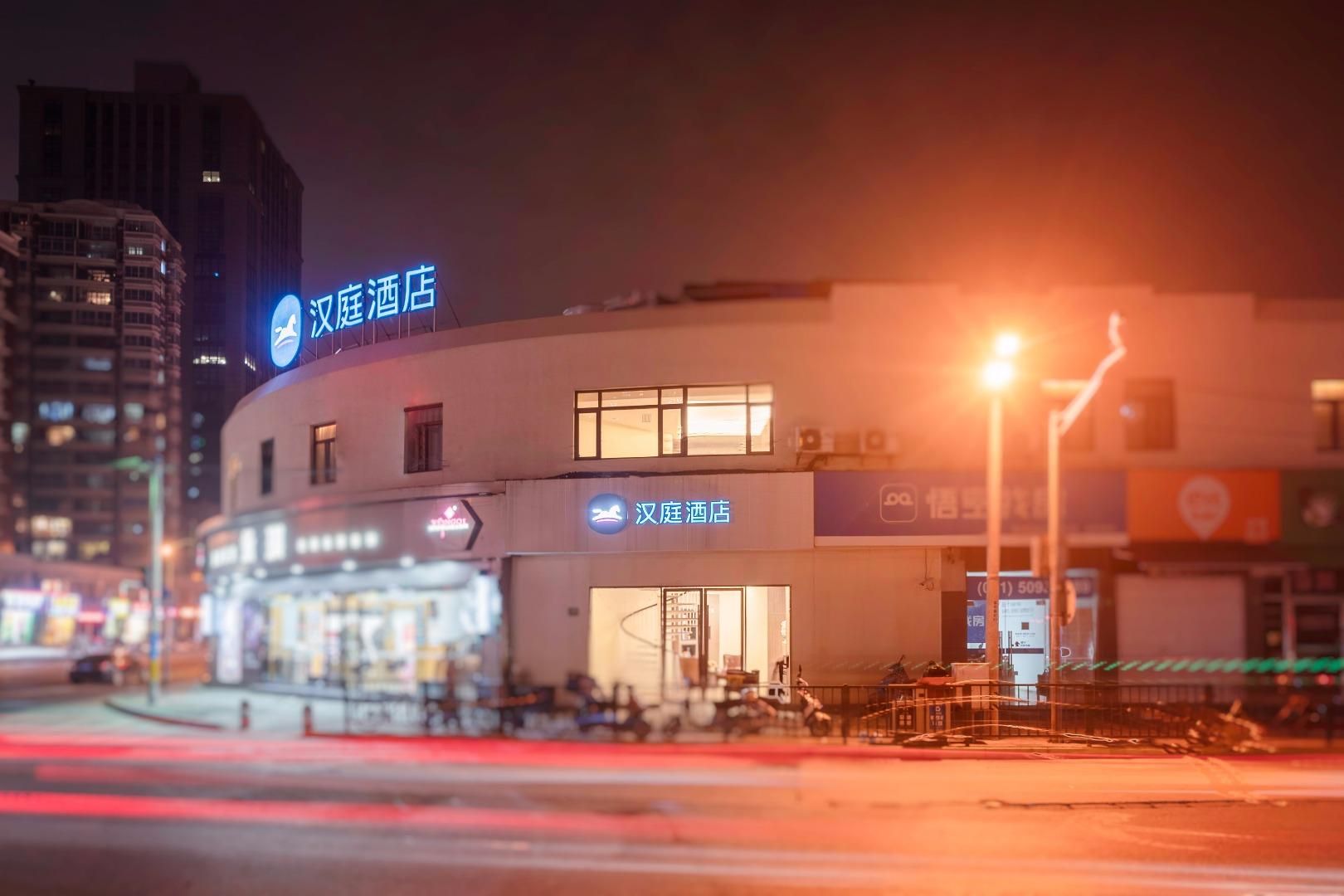 A hotel with a prominent sign, a visible entrance, and a street in the foreground.
