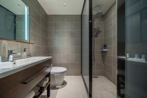 Une salle de bain moderne avec une douche à parois de verre, des toilettes blanches et un meuble-lavabo avec un miroir.